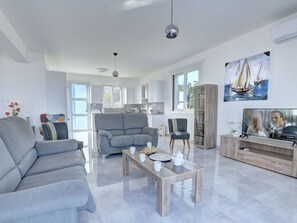 Ein modernes Wohnzimmer mit einem grauen Sofa, einem Holztisch und einem Fernseher.