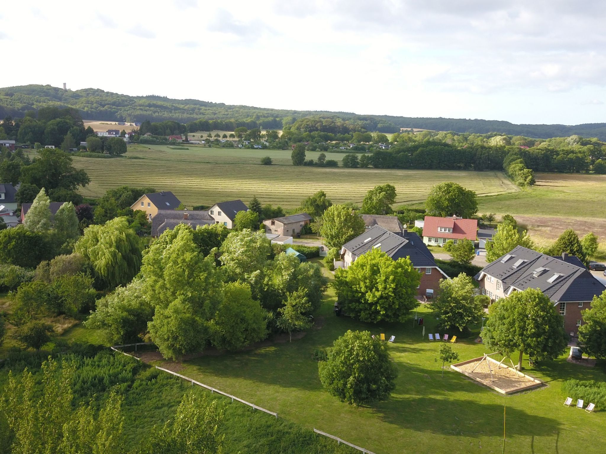 Een woonwijk met huizen, groene velden en een heuvel op de achtergrond.