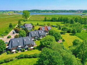Un quartiere residenziale con diverse case, cielo sereno e un lago sullo sfondo.