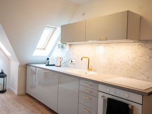 Eine moderne Küche mit Oberlicht, Einbauofen und Marmor-Spritzschutz.