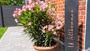 A potted plant with pink flowers in front of a building with a sign that reads "Willkommen" (Welcome). - Schule Altes Land by Interhome (Jork)