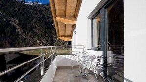 Un balcon avec une table et des chaises, un plafond en bois et une vue sur les montagnes.