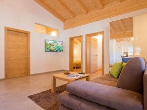 A modern living room with wooden ceilings, a sofa, a coffee table, and a TV on the wall. - Engelswand Appart by Interhome (Umhausen)