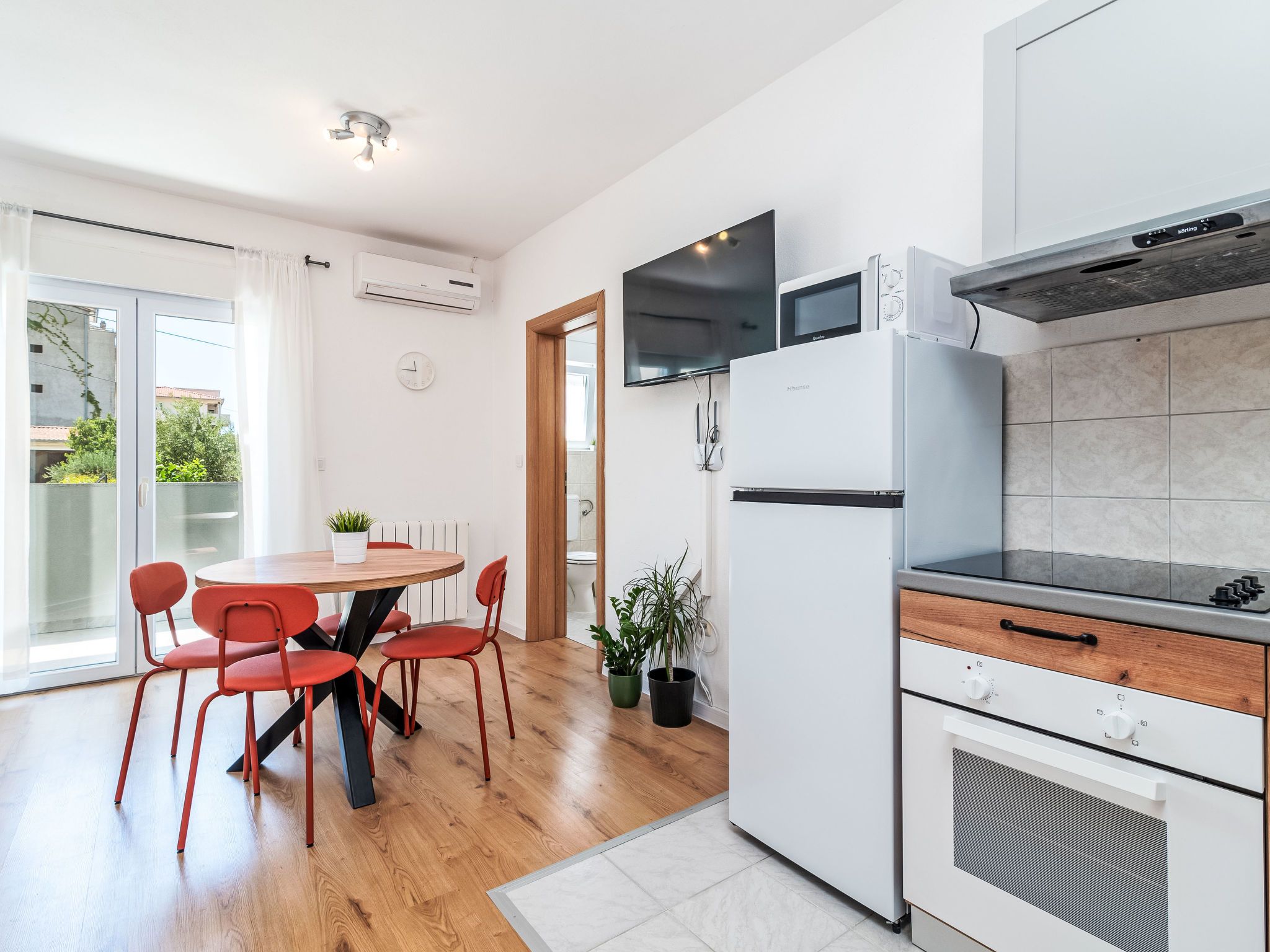 A modern kitchen with a dining area, featuring a built-in microwave, oven, and a flat-screen TV.