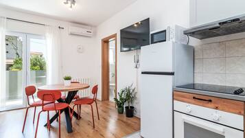 A modern kitchen with a dining area, featuring a built-in microwave, oven, and a flat-screen TV.