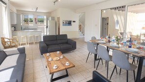 Un salon moderne avec un canapé, une table basse et un coin repas comprenant des chaises et une table mise pour le repas.