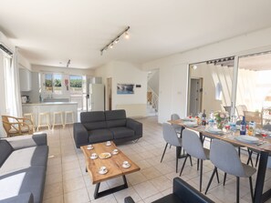 A modern living room with a sofa, a coffee table, and a dining area with chairs and a table set for a meal. - Ferienvilla "Holiday Villa" mit privatem Pool by Interhome (Paralimni)