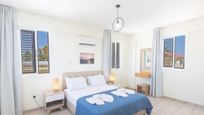 Une chambre d’hôtel avec un lit, des lampes de chevet, une petite table, un miroir et une fenêtre donnant sur un paysage agréable.