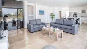 Een moderne woonkamer met twee grijze banken, een houten salontafel en een uitzicht op de stadsgezicht door grote ramen.