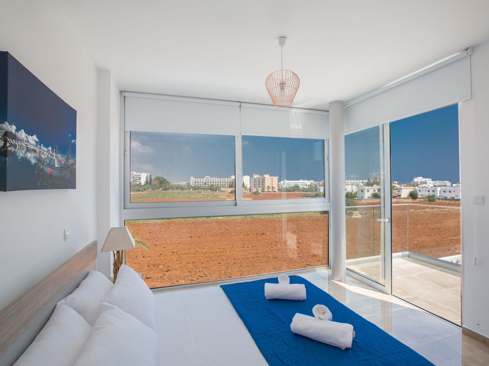 A modern bedroom with a large bed, a view of the city, and a balcony.