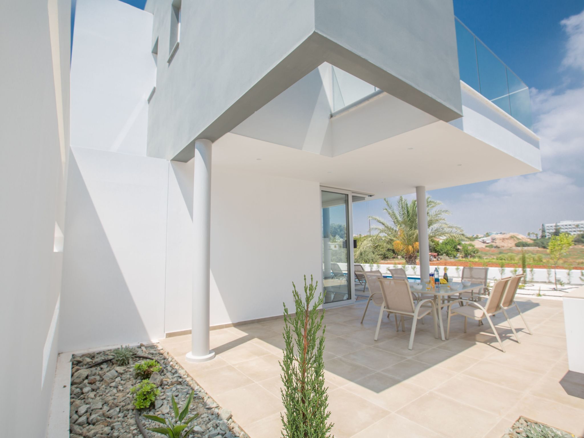 Une terrasse extérieure moderne, dotée d’un espace repas, d’une piscine et offrant une vue sur le paysage environnant.