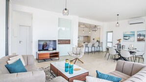 Ett modernt vardagsrum med en tv, soffor och en matplats med stolar och ett bord.