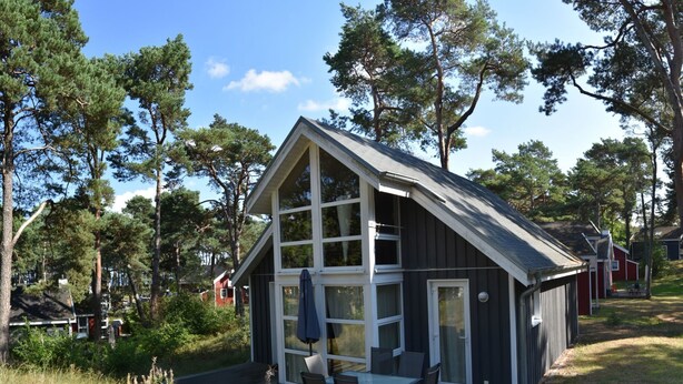 Een chalet met een ruim terras, een eethoek en een overdekte zithoek.