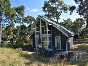 Eine Hütte mit einer großen Terrasse, einem Essbereich und einer überdachten Sitzgruppe im Freien.