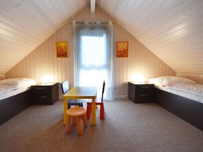 Ein gemütliches Schlafzimmer im Dachgeschoss mit zwei Betten, einem Esstisch und Stühlen.