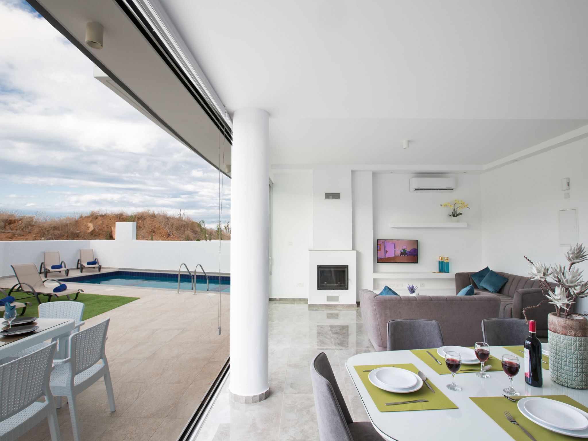 A modern living room with a pool, dining area, and a TV.