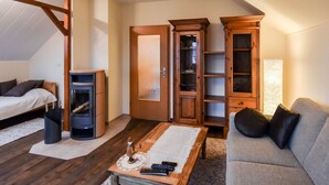 Ein gemütliches Wohnzimmer mit einer Couch, einem Couchtisch mit Fernbedienungen, einem Kamin und Holzelementen.