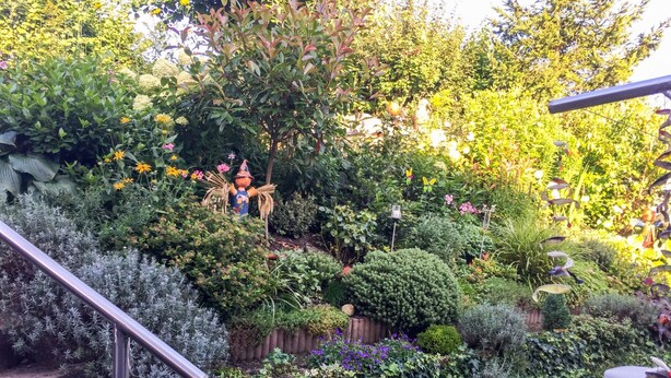 Ein Garten mit verschiedenen Pflanzen und einer verzierten Strohfigur.