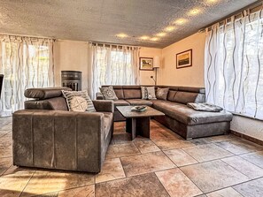 Ein Wohnzimmer mit einem Ecksofa, einem Couchtisch und einem Kamin.