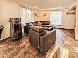 Ein Wohnzimmer mit Ecksofa, Kamin und Fliesenboden.