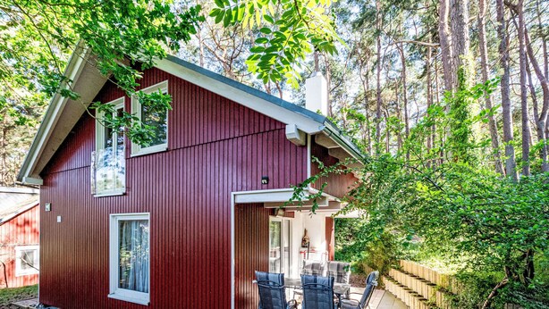 Una casa de madera roja con un patio y mobiliario exterior.