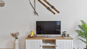 Ein modernes Wohnzimmer mit einem HolztV-Schrank, einem Flachbildfernseher und dekorativen Elementen wie einer Uhr und Holzstangen.