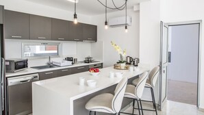 Una cucina moderna con isola centrale, elettrodomestici integrati e illuminazione a sospensione.