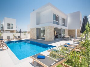 Uma casa moderna de dois andares com piscina, área de estar externa e fachada de pedra.
