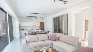 Ein modernes Wohnzimmer mit einer Eckcouch, einem Holztisch und einer Küche im Hintergrund.