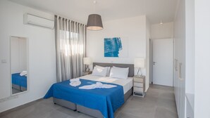 A modern hotel room with a large bed, a bedside table with lamps, a mirror, and a blue artwork on the wall. - Schöne Villa Olivine Pearl OL5 mit Garten by Interhome (Protaras)