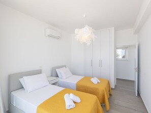 A hotel room with two beds, a white air conditioning unit, a white door, and a view of the outside through a window. - Protaras Olivine Villa OL9 by Interhome (Protaras)