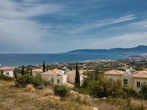 A coastal residential area with houses featuring flat roofs and solar panels, overlooking a sea and distant mountains. - Latchi Ferienvilla EV20 by Interhome (Agios Georgios Pegeias)