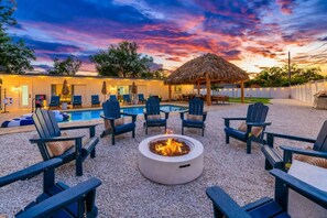 An outdoor seating area with a fire pit, lounge chairs, and a pool in the background. - Luxury 5BR  Heated Pool, Pickleball & Hot Tub (Seminole)