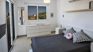 Une chambre à coucher moderne, avec un lit, des tables de chevet, une commode et une fenêtre donnant sur un beau paysage.
