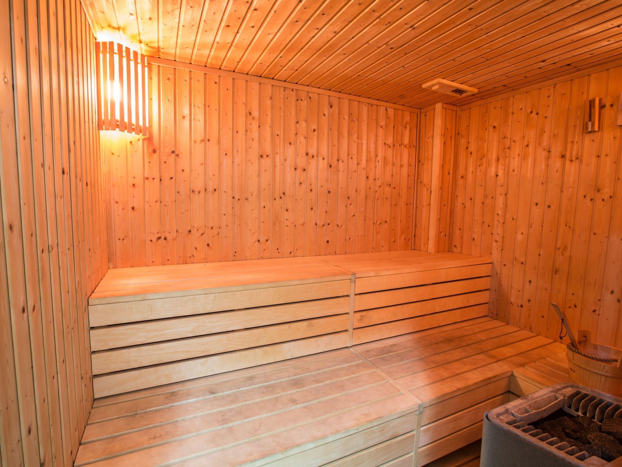 Una sauna de madera con bancos y una pileta de piedra.