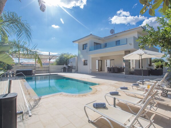 Uma casa moderna com dois andares, piscina, área de estar externa e um alpendre.