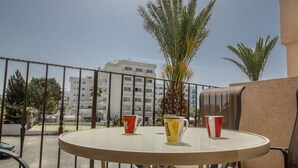 Una mesa redonda con dos sillas en un balcón, con vistas a un paisaje urbano con edificios y palmeras.