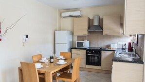 Una cocina compacta con una mesa de comedor lista para cuatro personas, un microondas, una estufa y un refrigerador.