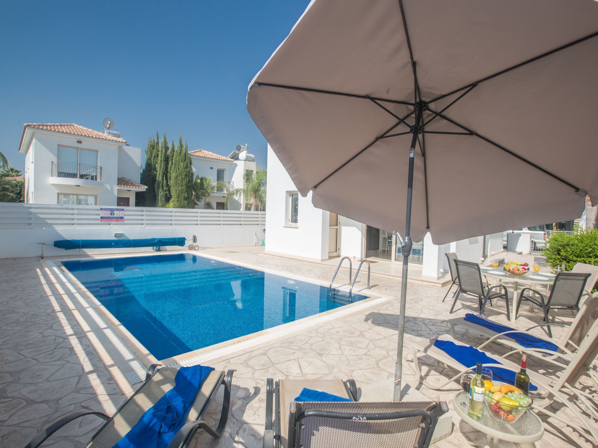 A swimming pool with lounge chairs and umbrellas, surrounded by buildings.