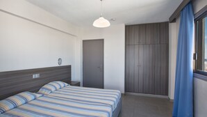 A modern hotel room with a bed, a wardrobe, and a window with curtains. - Komfortable Wohnung mit Balkon by Interhome (Ayia Napa)
