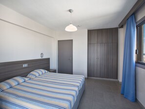 Ett modernt hotellrum med en säng, en garderob och ett fönster med gardiner.