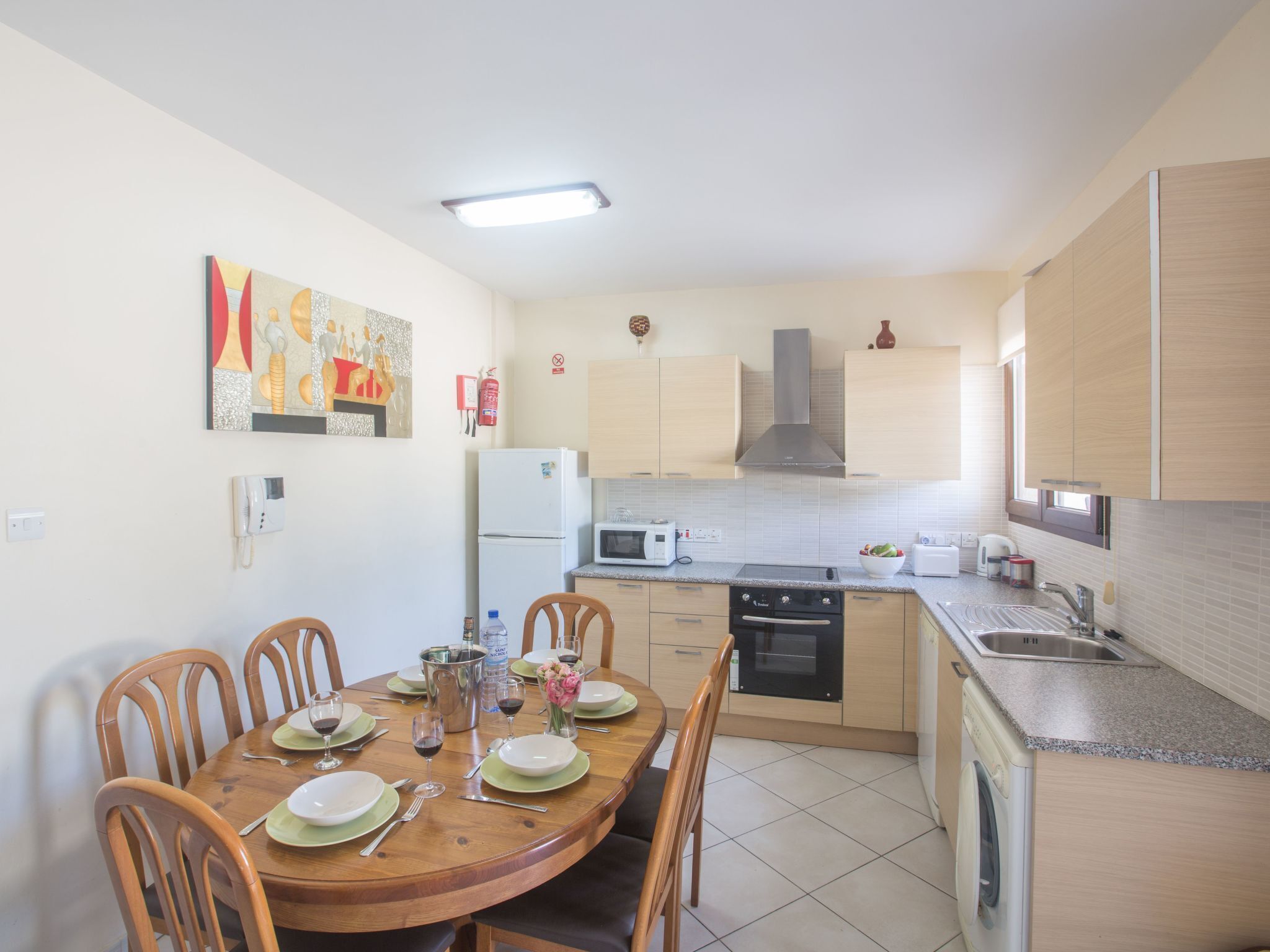 A modern kitchen with a dining area, featuring a microwave, stove, and sink.