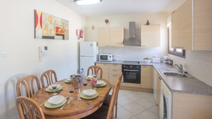 A modern kitchen with a dining area, featuring a microwave, stove, and sink. - Moderne Erdgeschosswohnung in Ayia Napa by Interhome (Ayia Napa)