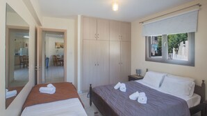 A bedroom with two beds, a wardrobe, a window with a view, and a mirror. - Moderne Erdgeschosswohnung in Ayia Napa by Interhome (Ayia Napa)