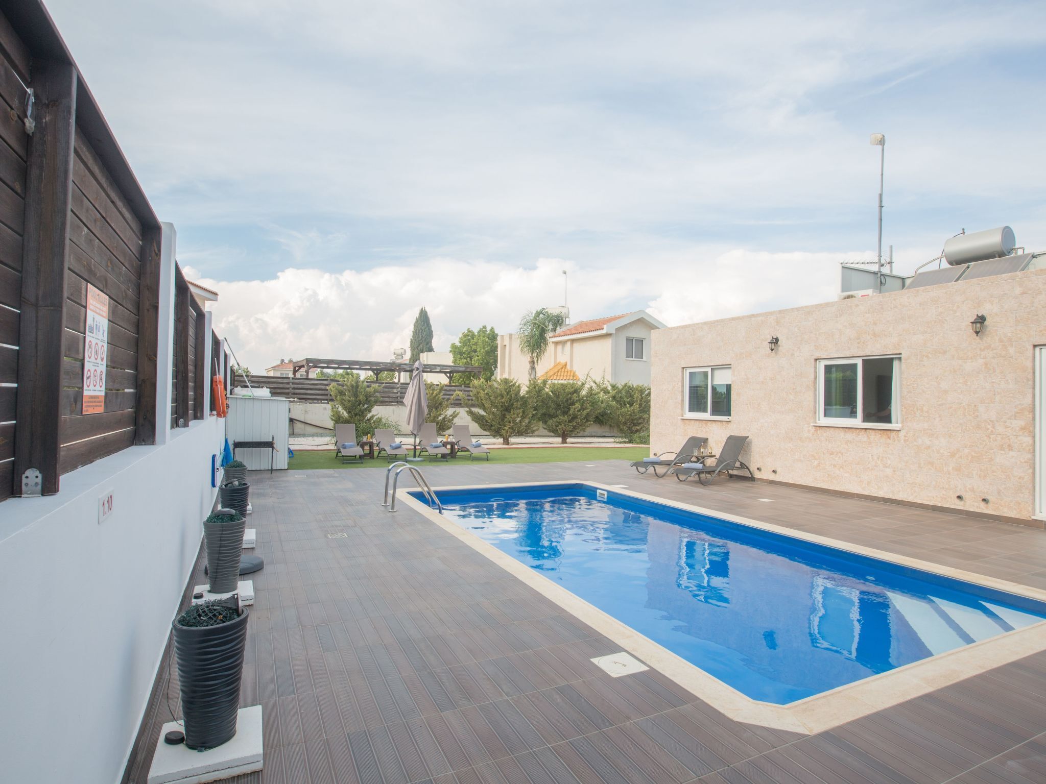 Une piscine sur le toit, dotée de chaises longues, d’une pergola et offrant une vue sur les bâtiments environnants.