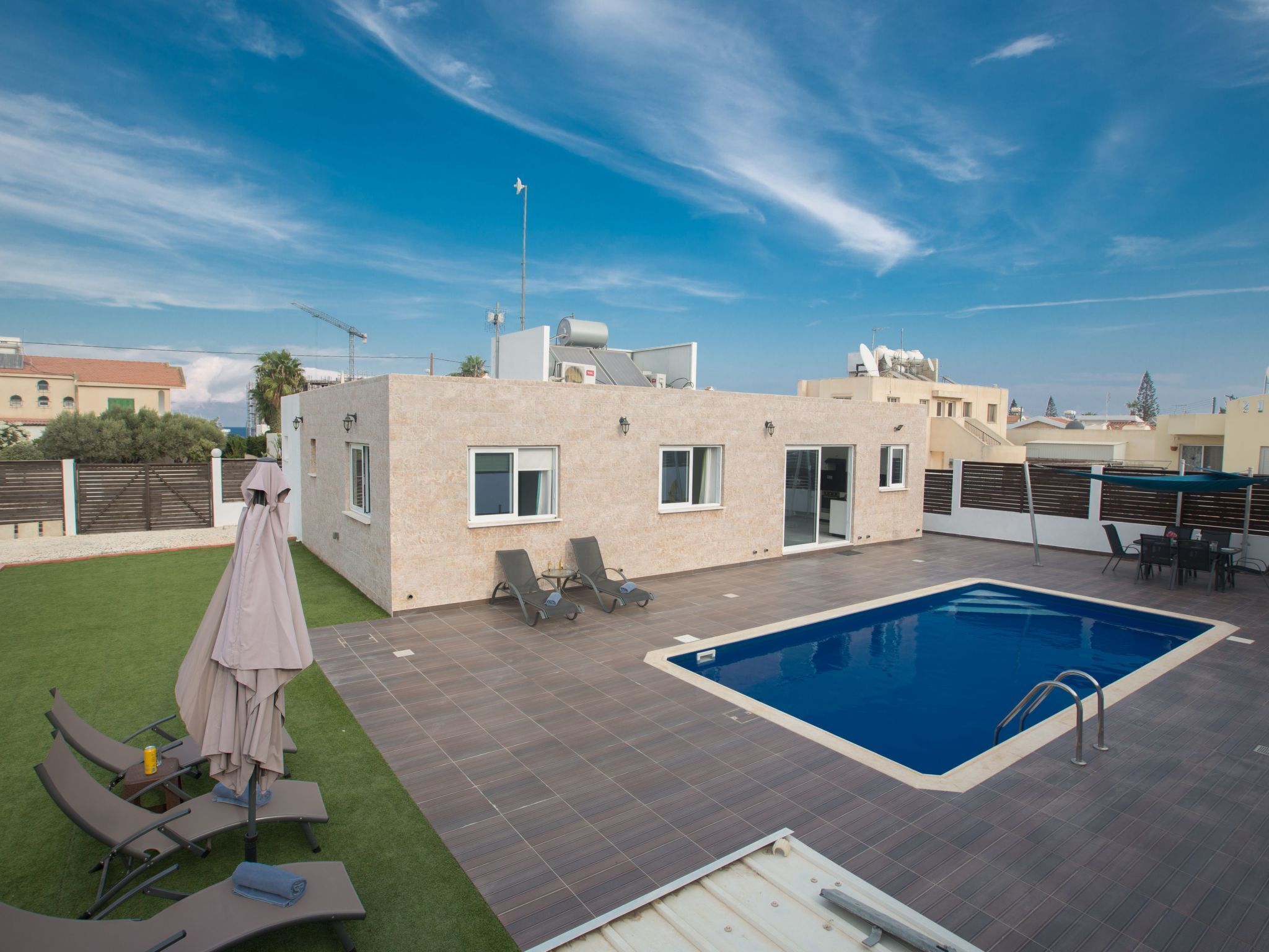 A rooftop pool area with a swimming pool, lounge chairs, and a covered seating area.