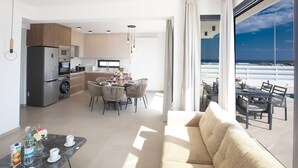 A modern apartment with a kitchen, dining area, and a balcony with a view of the ocean.