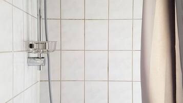 Une douche avec des robinets chromés et un mur carrelé.