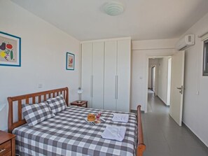 Ein Schlafzimmer mit kariertem Bettbezug, einem Holzkopfende, einem Nachttisch mit Lampe und einem Kleiderschrank mit Schiebetüren.