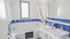 Une salle de bain moderne avec une baignoire, deux lavabos, des toilettes et une fenêtre.